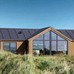 Et sommerhus bygget i bæredygtige materialer og med store vinduer.