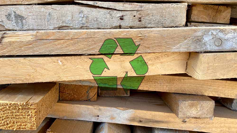 En stak træ med genbrugssymbol henover