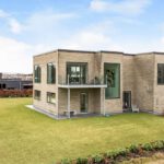 Hvidt flot moderne hus med solskin og græsplæne i et plan