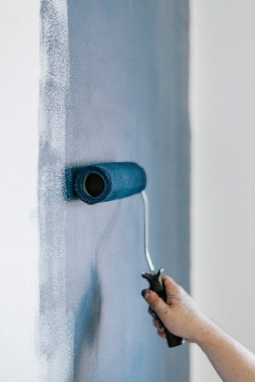 person i gang med at male blå maling på en hvid væg