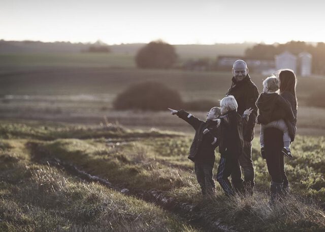 En familie med børn står på en mark i jagten på at vælg den rigtige byggegrund.