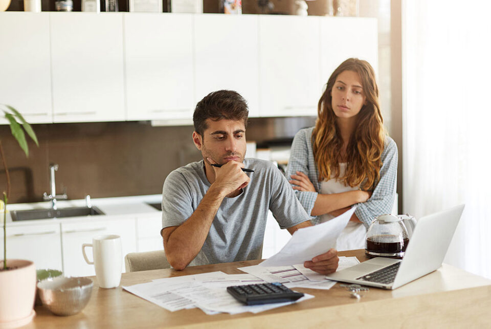 Kvinde og mand foran en computer og er ved at lægge et budget over sit sommerhusbyggeri